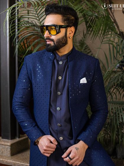 A client looking cool and confident in a navy blue Indo-Western jacket with a subtle shimmer. The modern, open-front style is layered over a matching kurta, creating a sleek, monochromatic look.