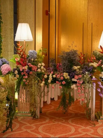 A long console table overflowing with a stunning variety of pastel flowers. The arrangement creates a beautiful floral runner, adding color and life to the indoor venue.