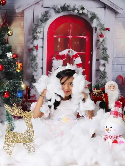 A playful moment as this little girl throws fake snow in the air during her fun-filled Christmas photoshoot.