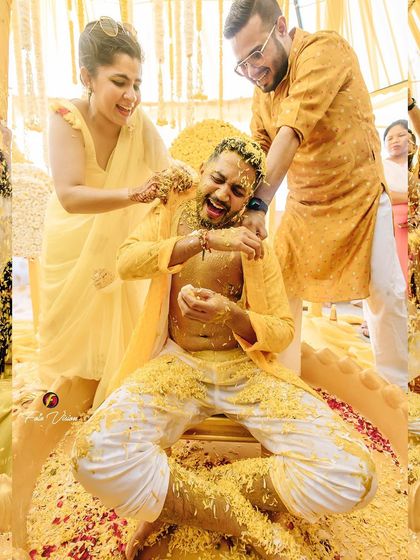 A candid shot of the groom getting playfully covered in turmeric by his friends and family. We capture the fun and teasing that is a big part of the Haldi ritual.