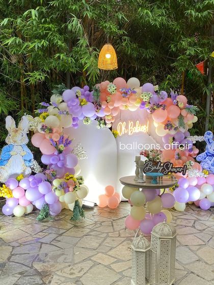 The 'Oh Babies' backdrop illuminated at night, with a neon sign, lanterns, and whimsical bunny cutouts creating a magical ambiance.