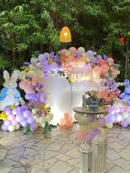 The 'Oh Babies' backdrop illuminated at night, with a neon sign, lanterns, and whimsical bunny cutouts creating a magical ambiance.