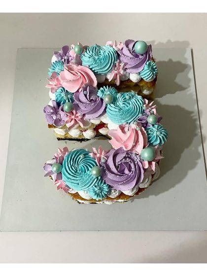A monogram cake in the shape of the number 5. This strawberry-flavored cake is decorated with beautiful pastel-colored rosettes, perfect for a 5th birthday.