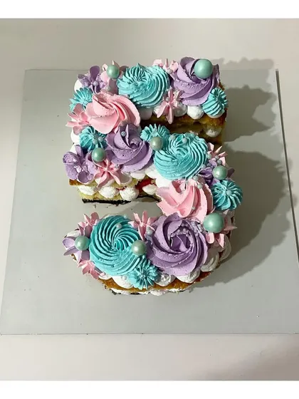 A monogram cake in the shape of the number 5. This strawberry-flavored cake is decorated with beautiful pastel-colored rosettes, perfect for a 5th birthday.