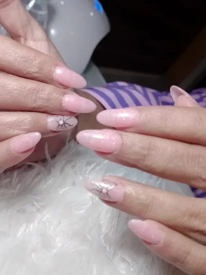 A closer view of the soft pink extensions, showing the delicate, minimalist butterfly art.