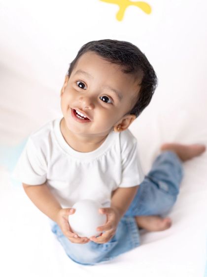 A close-up of our little artist, holding an egg and looking up with a curious smile.