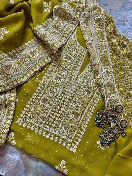 A folded view of the suit, emphasizing the rich mustard green hue and the intricate handwork.