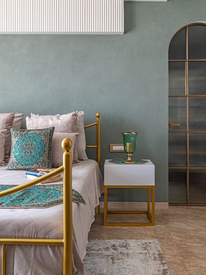 A full view of the 'Eternity' master bedroom, showcasing the gold bed frame against the sage green wall. The design feels both regal and calming.