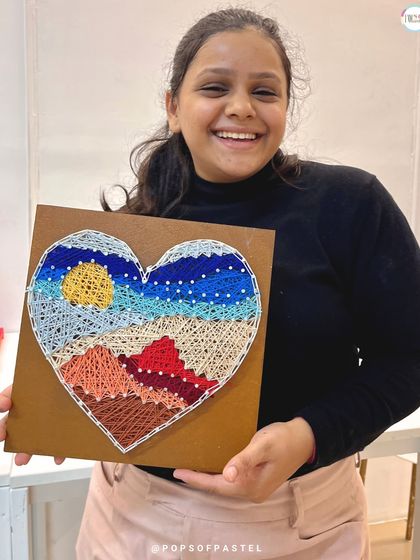 The joyful result of a creative date night. This participant beams as she shows off her heart-shaped landscape string art.