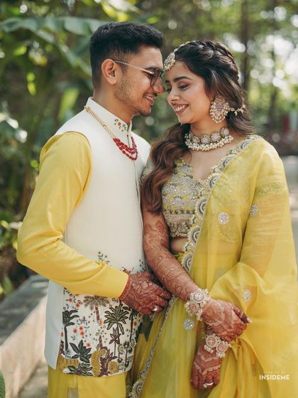 A sweet, happy moment. The close-up shows the bride's glowing skin and the intricate details of her jewelry and hairstyle.