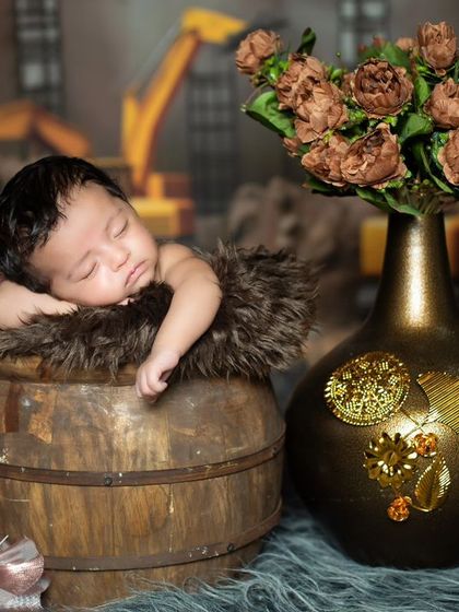 A newborn sleeping in a barrel with a construction site backdrop. A unique concept for a future builder.