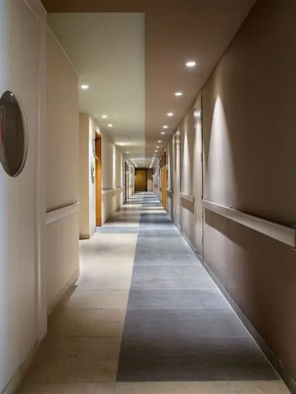 A corridor should do more than carry footsteps; it should carry conversations. We use lighting and flooring patterns to make transitional spaces like this one feel intentional and engaging, shaping the experience of moving through a building.