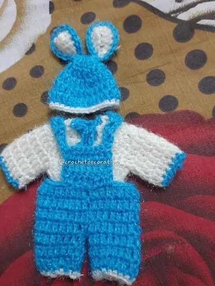 This playful crochet jumpsuit for Laddu Gopal features a white top with blue overalls and an adorable matching cap with bunny ears. It's a unique and modern outfit for your idol.