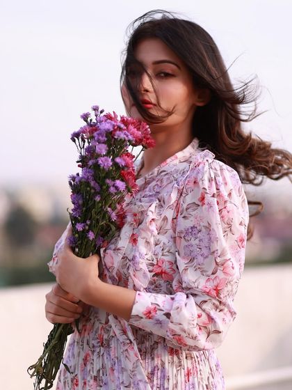 A strong and confident pose, holding the flowers like a shield. Her direct gaze is powerful, and the wind adds a dramatic flair.