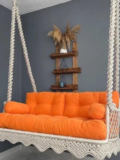 Our macrame sofa swing with a bright orange cushion. This piece adds a pop of color and a lot of comfort to any room, perfect for lounging with family and friends.