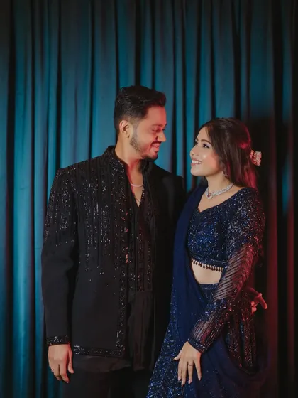 A perfect match. Her popping pink makeup complements his classic black sherwani, creating a stylish couple look.
