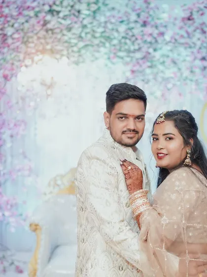 A classic portrait of the newly engaged couple against a beautiful floral backdrop. The bride rests her hand on the groom's chest, showcasing her ring and their new status as a couple.