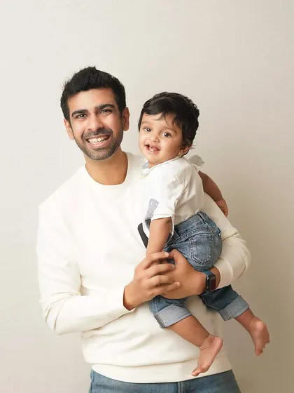 A father holds his son, both smiling brightly for the camera. This is a classic portrait that captures the happy bond between them.