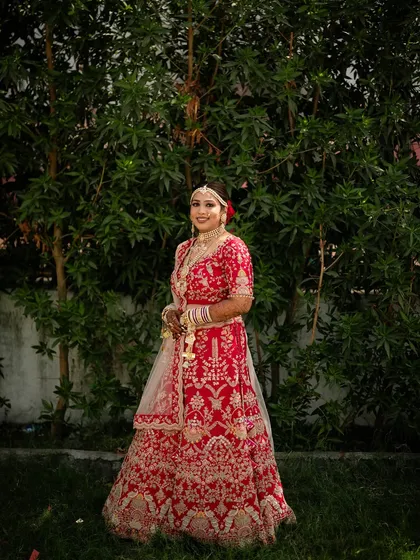 A full-length shot of the bride in an outdoor setting, showing the beautiful flare of her embroidered lehenga.