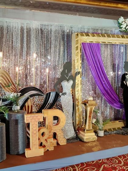 Another angle of the sangeet photo booth, showing the 3D initials of the couple and the elegant mix of gold, purple, and silver elements.
