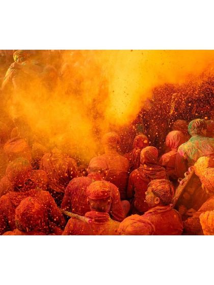 An explosion of orange powder fills the frame, a testament to the wild and uninhibited joy of the Holi festival.