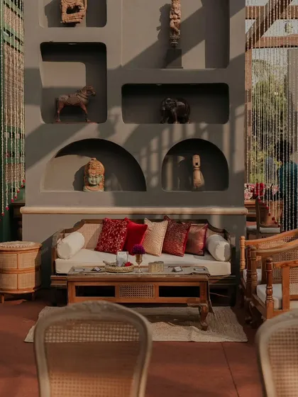 Sunlight streams into a beautifully styled lounge area, highlighting the textures of the furniture and the artifacts in the decorative wall niches.