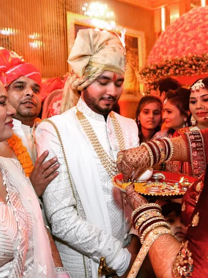 A candid shot during the wedding rituals. The focus is on the groom as he participates in the ceremony, surrounded by family.