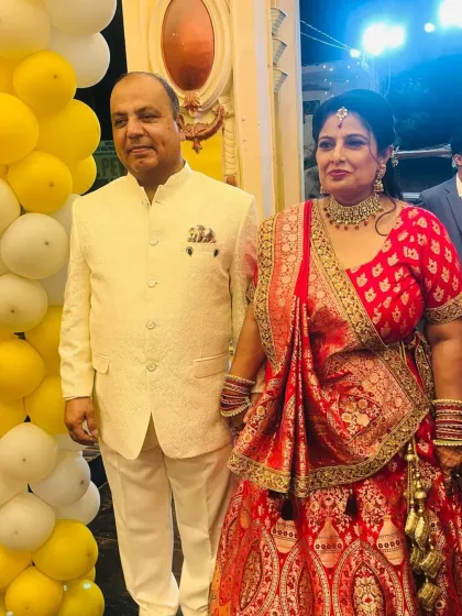 A happy client couple celebrating their special day. She is wearing a beautiful red and gold lehenga, perfectly complemented by his elegant ivory sherwani.