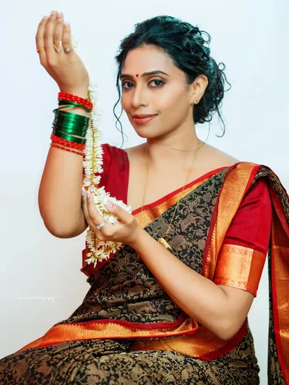 A joyful and candid moment, with the bride holding a string of jasmine flowers. Her smile is genuine and lights up the frame.