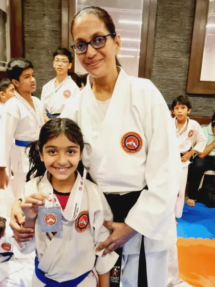 A student and her Sensei share a proud moment after a medal win. The bond between teacher and student is at the heart of our academy's success.