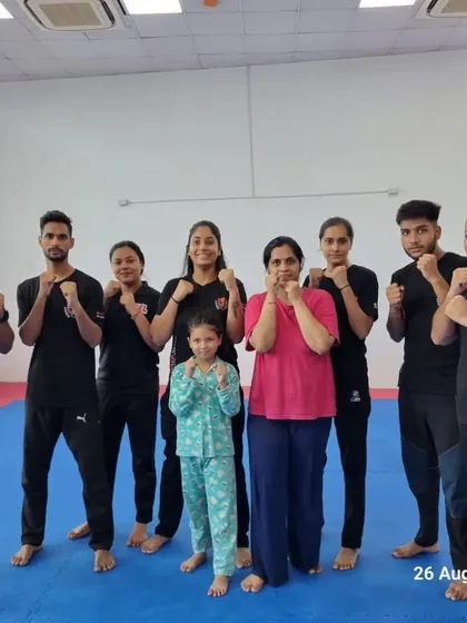 A group photo of a mixed batch, including men, women, and a young child, all in a fighting stance.