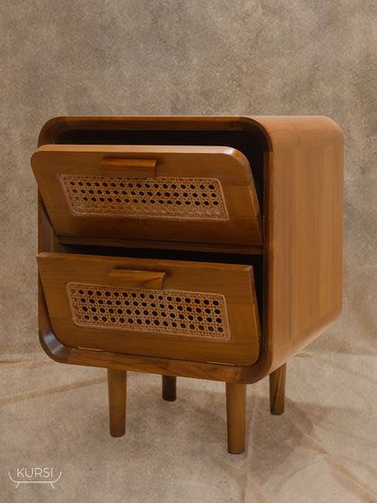 The 'Cuo' side table, featuring a solid teak frame with curved sides and two drawers with rattan-fronted, openable shutters. A sophisticated and practical piece for any bedroom.