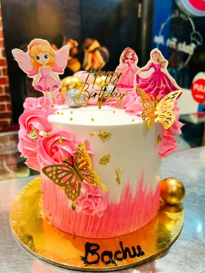 A pink and gold fairy-themed cake with golden butterflies.