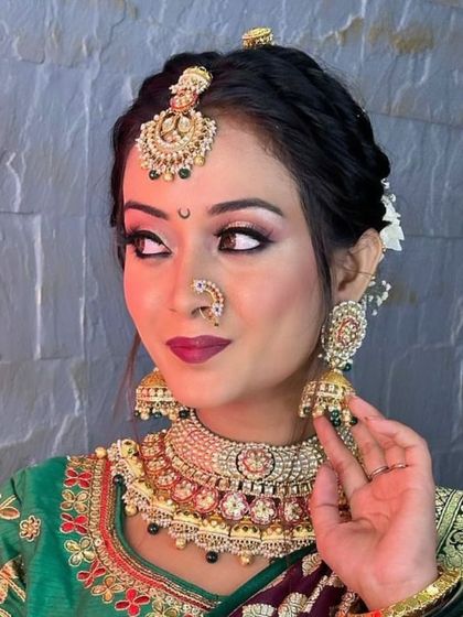 This bride looks gorgeous in a rented choker set with black bead detailing, a traditional nath, and large jhumkas, creating a striking contrast with her green saree.