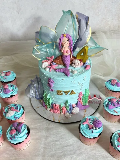 Here's a closer view of the pastel mermaid cake, highlighting the shimmering, translucent sugar sail and the adorable fondant mermaid. The sides of the cake are decorated with colorful coral and seashells.