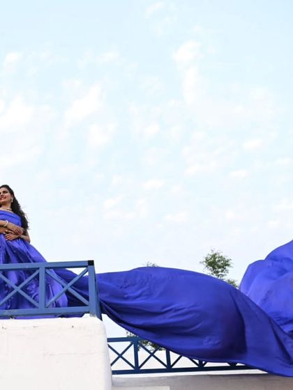 A dramatic angle from a balcony, showcasing the immense size and rich color of the royal blue infinity trail. This is a gown that guarantees a "wow" moment.