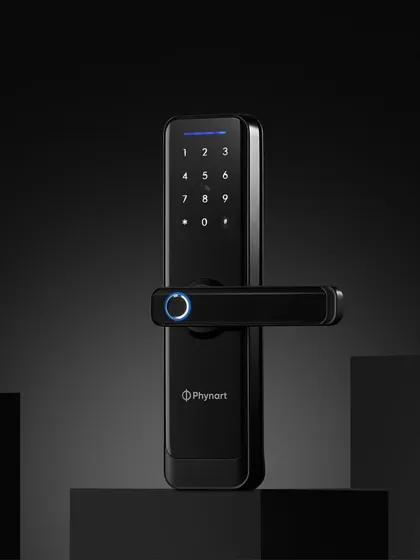 A hero shot of the Phynart smart lock, placed on geometric blocks. The dark, moody lighting with the glowing blue fingerprint sensor gives it a futuristic and secure look.