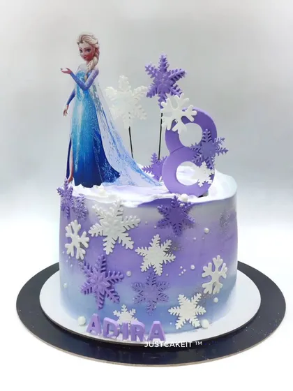 This Frozen theme cake was customized with a purple color scheme to match the birthday girl's dress. The edible snowflakes and Elsa topper create a beautiful, personalized winter scene.