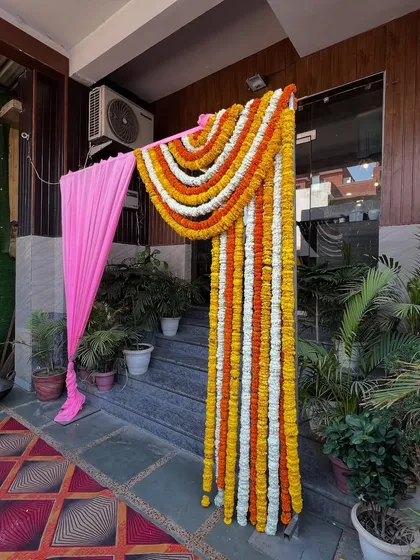 A beautiful entrance decoration using a curtain of marigold garlands in yellow, white, and orange.