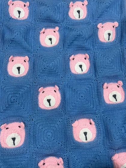 A close-up, flat-lay view of our bear-themed baby blanket in a lovely blue and pink combination. You can see the detail in each crocheted square.