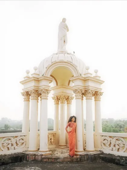 A wide, architectural shot for Studio Swatti Kapoor. The model in a saree is framed by a beautiful white gazebo, creating a grand and ethereal fashion photograph.