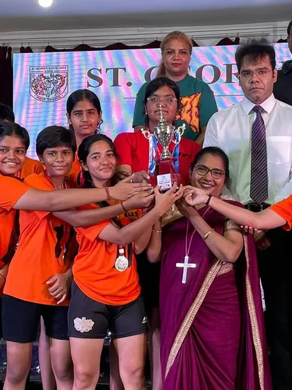 The team posing with their trophy and medals, celebrating their success with school officials.