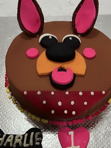 A close-up of Charlie's custom cake, featuring big ears and a bandana. We can add personalized details like names and ages to any order.