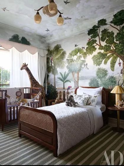 This image from the AD spread showcases the room's layout, with the woven cane bed and classic wooden crib set against the immersive, hand-painted jungle walls.