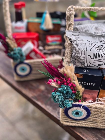 Jute baskets filled with gourmet snacks and adorned with evil eye charms and colorful dried floral bouquets. This is a perfect example of how I blend rustic textures with vibrant, thematic details.