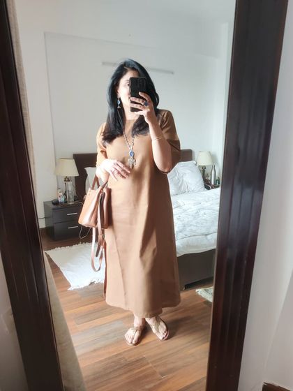 A mirror selfie of the brown anti-fit dress, showing how it looks with a matching bag before heading out.