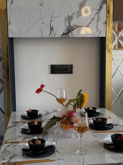 A close-up of the beautifully set, space-saving dining table. The combination of marble, reflective surfaces, and elegant tableware creates a luxurious dining experience.