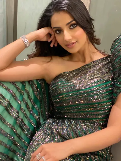 A close-up, seated portrait in the sparkling green gown. This intimate shot captures a moment of quiet confidence amidst the glamour of the event.