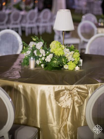 A table centerpiece with a lamp and a large gold bow, part of the elegant decor for a Goa dinner party.