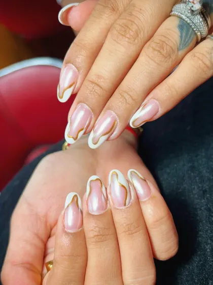 A creative and artistic French manicure featuring a pearlescent base with abstract gold and white swirls along the edges.